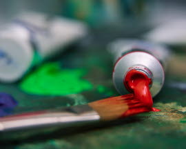 A tube of paint and a paintbrush are lying on a table.