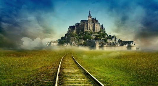 A city surrounded by a wall with a castle on a hill visible at the end of a pair of railway tracks.